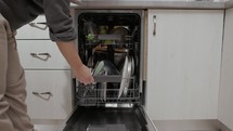 A Woman's Hands is Taking Clean Plates From the Dishwasher - Close Up
