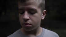 A sad young man crying with tears on his face in cinematic slow motion.