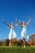 Two women dancers outdoors dancing on the grass, autumn trees in the background