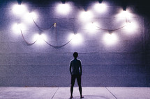 silhouette of a man with back to the camera looking at lights 