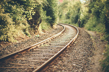 A man walks by a railroad track through the countryside.