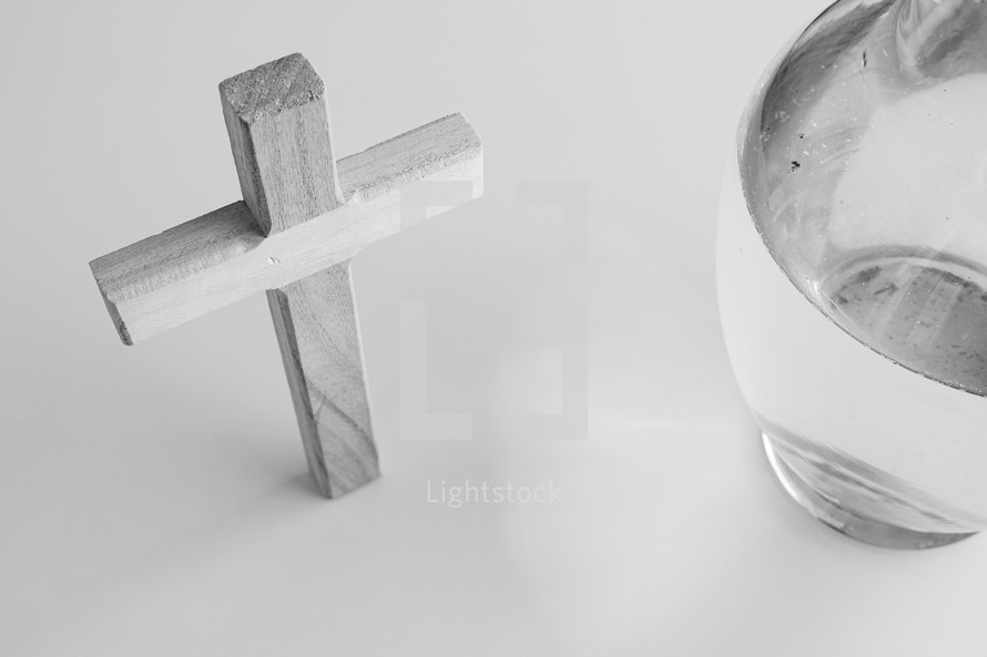 black and white image of a wooden cross and vase of water on a white background