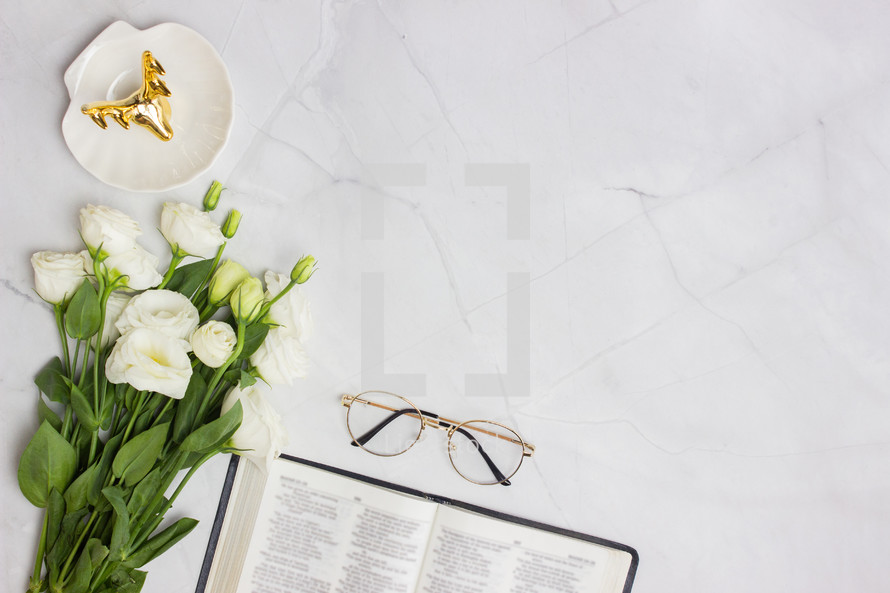 white roses on a white marble desk and open Bible 