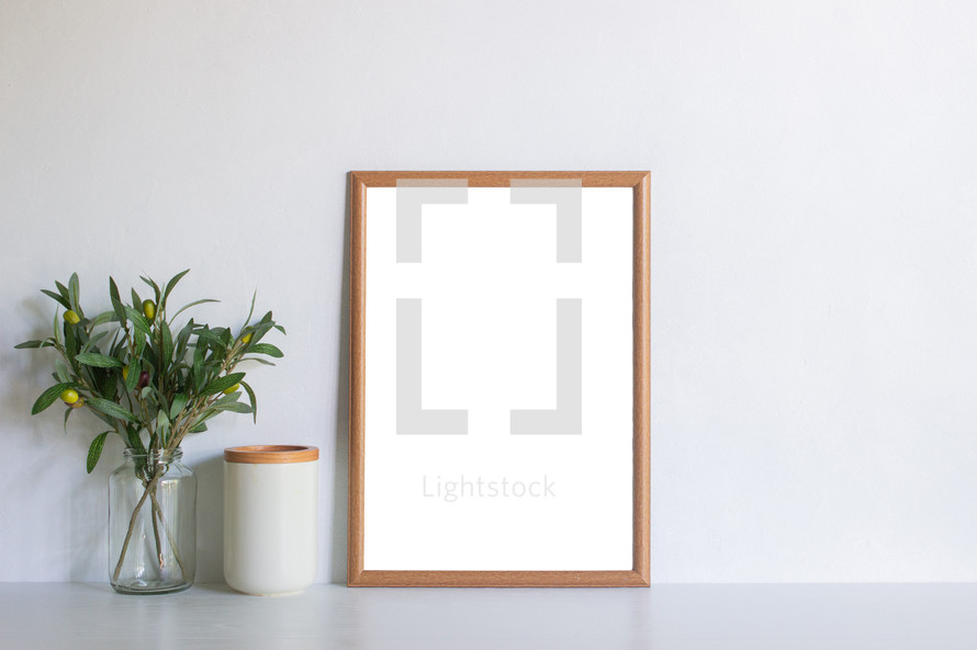 blank frame and olive branches in a vase 