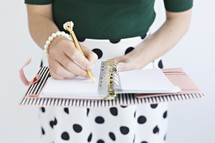 a woman writing in a planner 