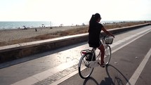 young woman riding a bicycle along a shore 