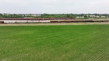 Freight train on the railroad by a cornfield in the country.