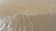 Sea wave washing Brazil written on the sand