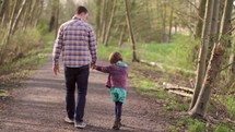 father walking holding hands with his daughter
