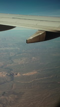 Plane flying over city, mountains, and desert