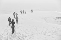 people walking on a beach in the fog 