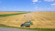 Aerial view of a combine and tractor harvesting on wheat field in summer day. 