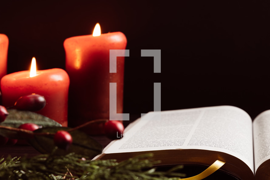 Christmas garland with berries, candles, and open Bible