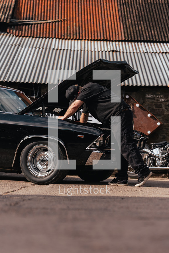 Mechanic repairing an American muscle car, vintage automobile repair workshop, car garage