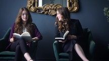 young women sitting and reading together and laughing