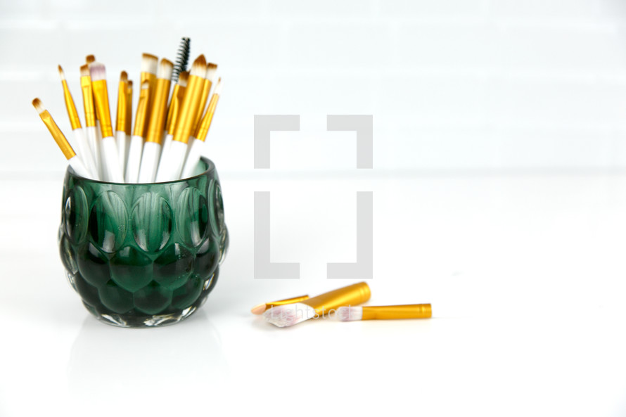 paint brushes in a green glass
