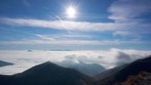 Low inversion clouds in the valley, Mountain hilly landscape, Sun in the blue sky