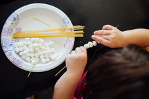 a child playing with spaghetti noodles and marshmallows to improve motor function 