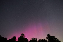 Night sky with some pillars of pink Aurora Borealis 