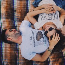Smiling couple laying on a blanket outside.