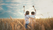 Portrait of happy little ukrainian children boys with maces - bludgeons in wheat field. Bulava, Ukraine, peace. Kids in traditional embroidery vyshyvanka shirts. Brothers, freedom, patriots.