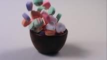 candy hearts falling into a bowl 