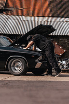 Mechanic repairing an American muscle car, vintage automobile repair workshop, car garage