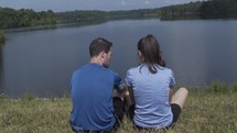 couple sitting on a shore by a lake 