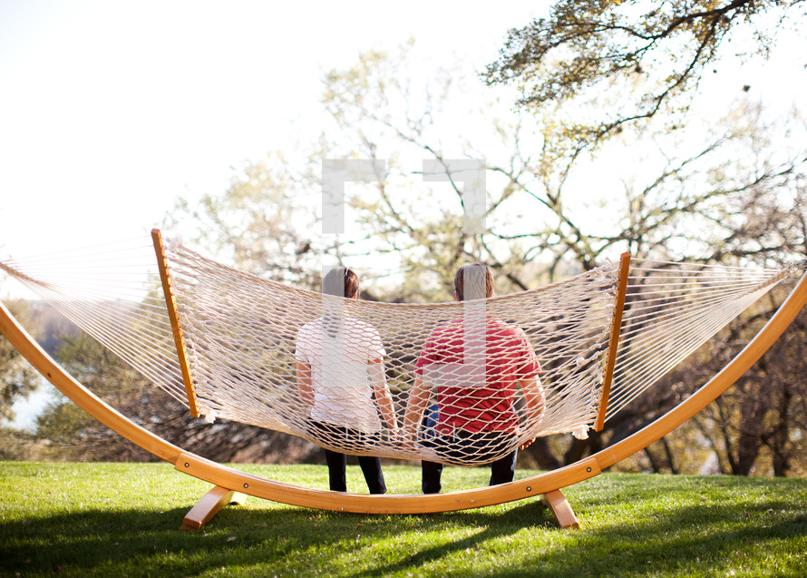man and woman sitting on a hammock