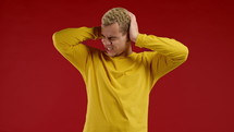 Annoyed man with shut ears on red background