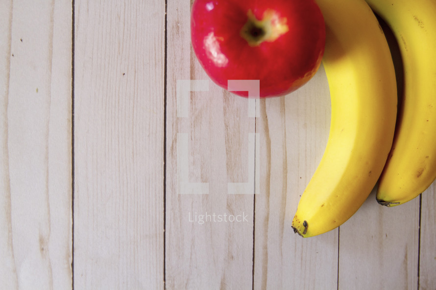 bananas and apple on a wood background 
