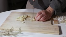 Female Hands Cut Garlic On A Wooden Board - Close Up