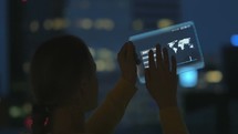 Woman using futuristic holographic tablet at night
