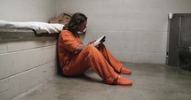 Convicted criminal, prisoner, sad man in prison or jail cell incarcerated for crime reading his bible.