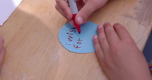 Young boy writing what he wishes for on piece of paper - close up on hands