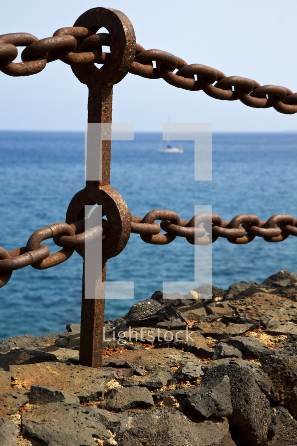 rusty metal chain in rock along a coastline 
