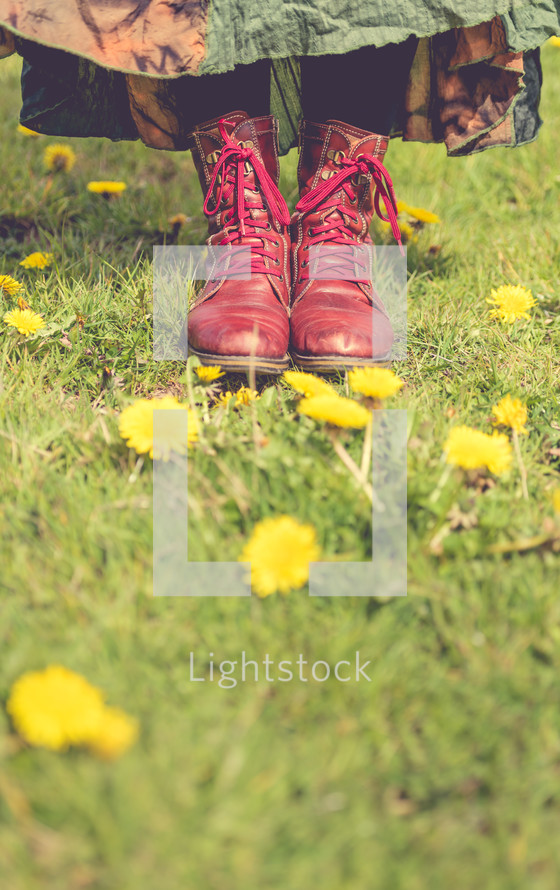 A woman in red boots standing in a field of flowers.
