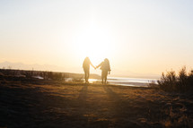 Two people holding hands in the glow of the sunset.