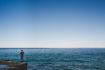 a man standing on a cliff near the ocean 