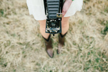 a woman with a vintage accordion camera around her neck 