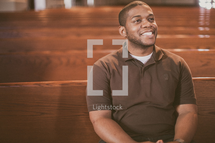 man sitting in a church looking up to God smiling 