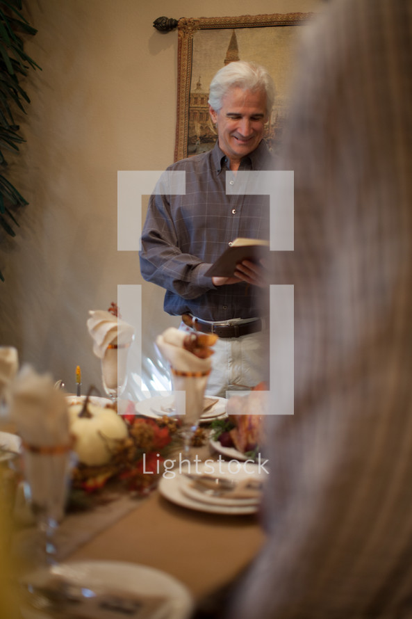 Man reading a Bible verse in prayer at a Thanksgiving table 