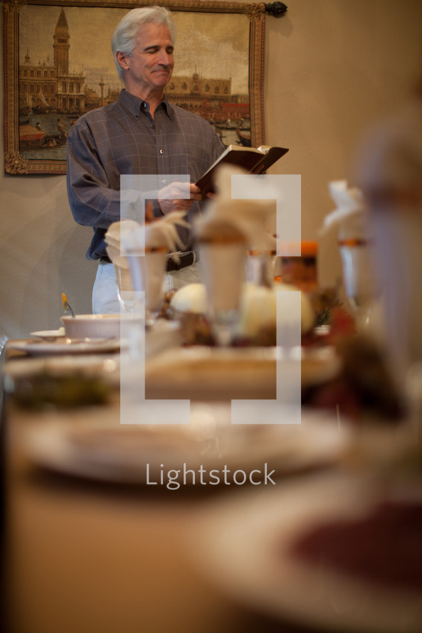 man reading a Bible at a Thanksgiving dinner table 
