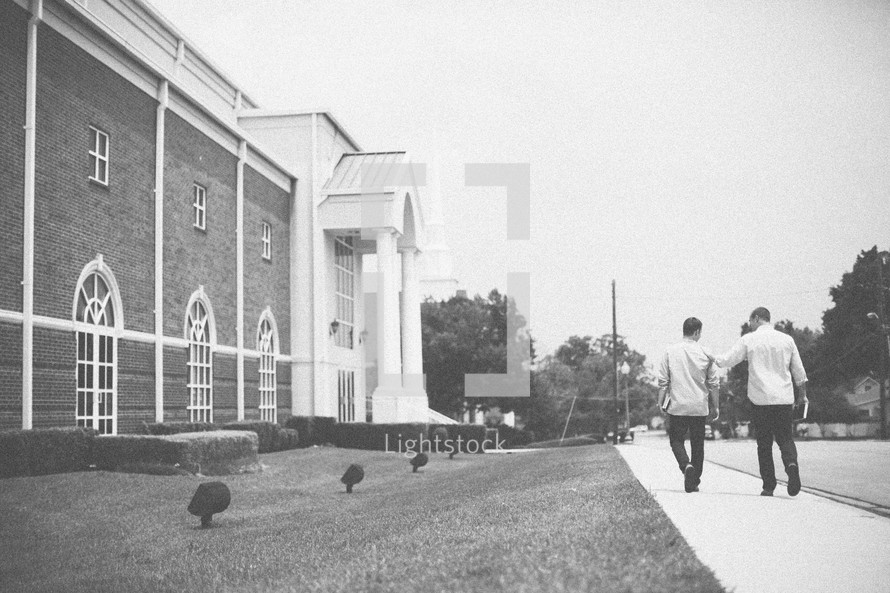 men walking down a sidewalk heading to church