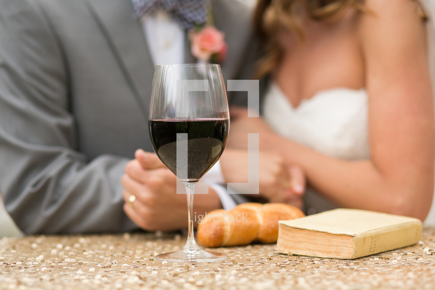 torso of a bride and groom and communion bread and wine 