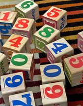 child's wooden number blocks spread out on a colorful rug