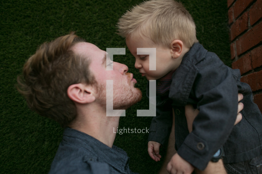father kissing his toddler son