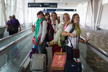 A group of young women walking through the airport with their suitcases