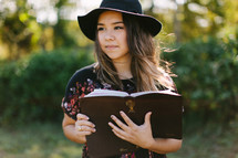 a teen girl in a hat reading a Bible 