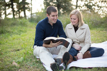 A couple reading the bible together outside